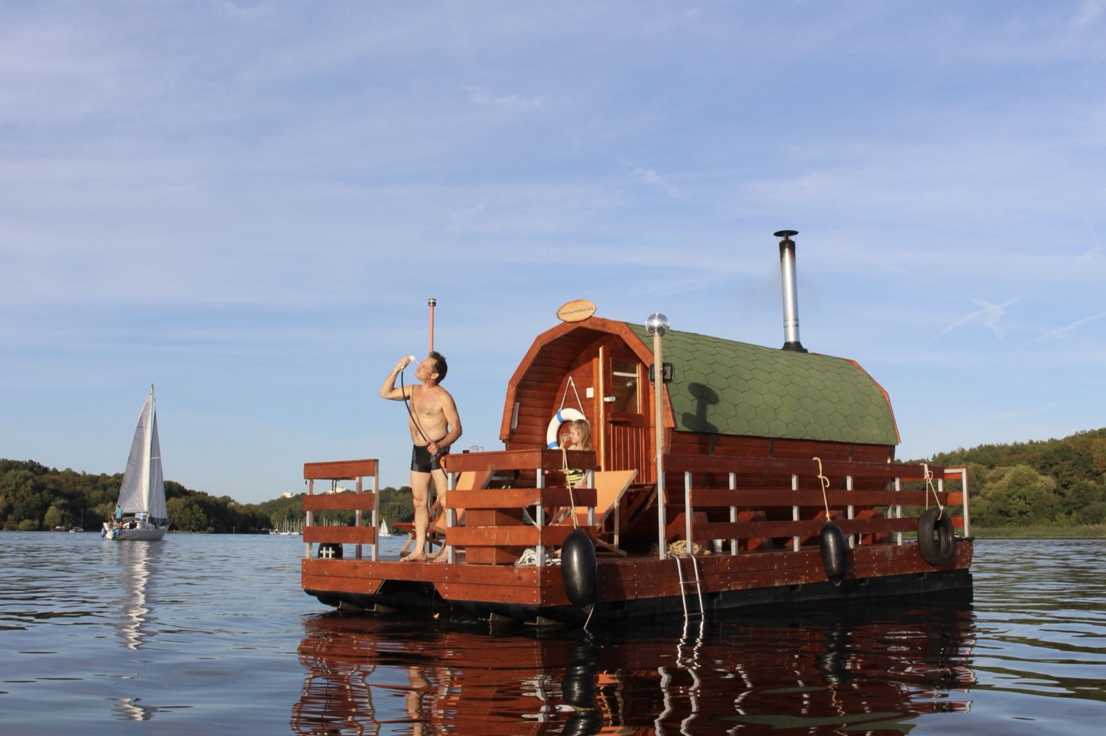 Mann auf dem Floss, im Hintergrund ein Segelboot